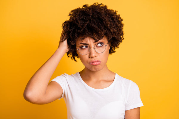 Woman with coily hair and glasses on an orange background