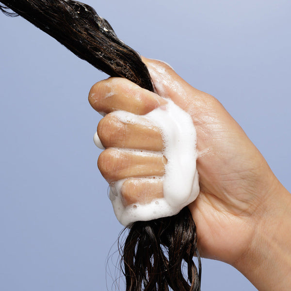 Hand applying shampoo to hair