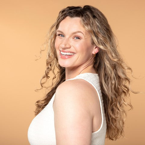 Smiling woman with beautiful, healthy wavy blonde hair, styled effortlessly to showcase natural texture and shine. Perfect representation of radiant, well-cared-for curls and waves.