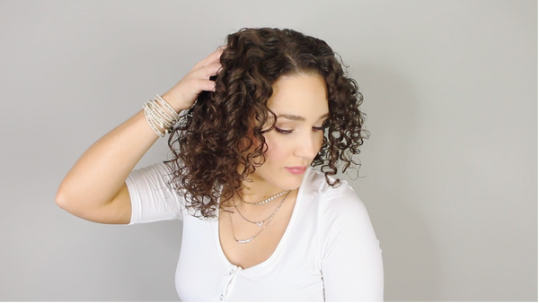 Woman running her fingers through her hair on a grey background