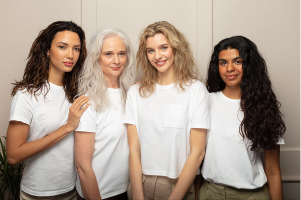 Four women with curly hair and white shirts 