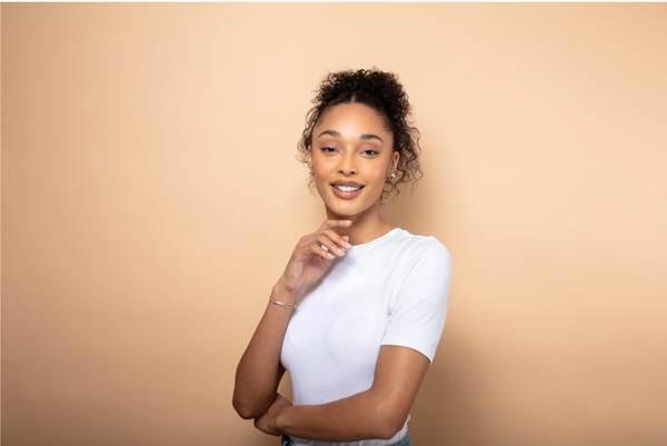 Woman with curly hair and a white T-shirt on an orange background