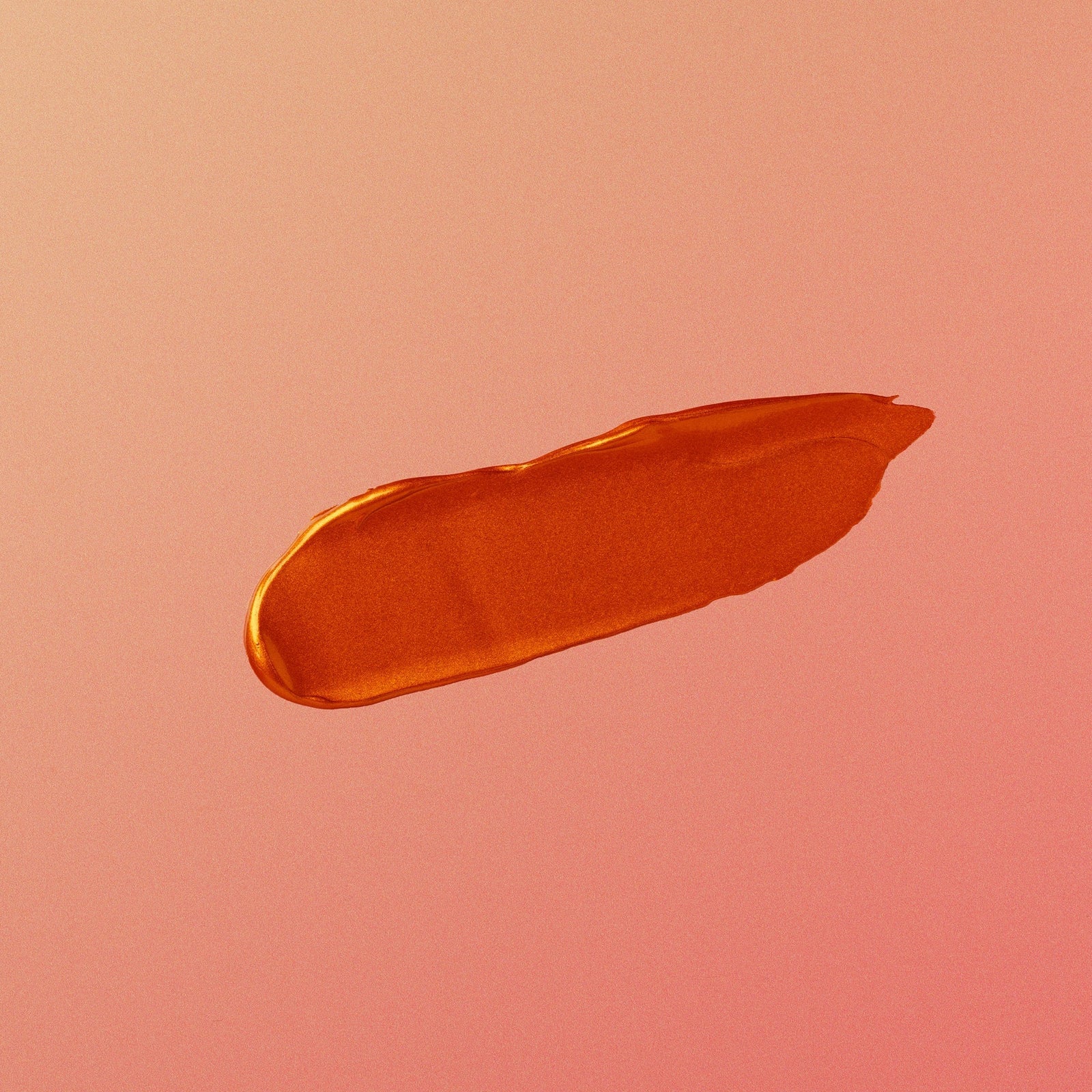 Orange lipstick swatch on a pink background