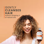 Woman holding a bottle of Curlsmith product with text about hair care on a beige background