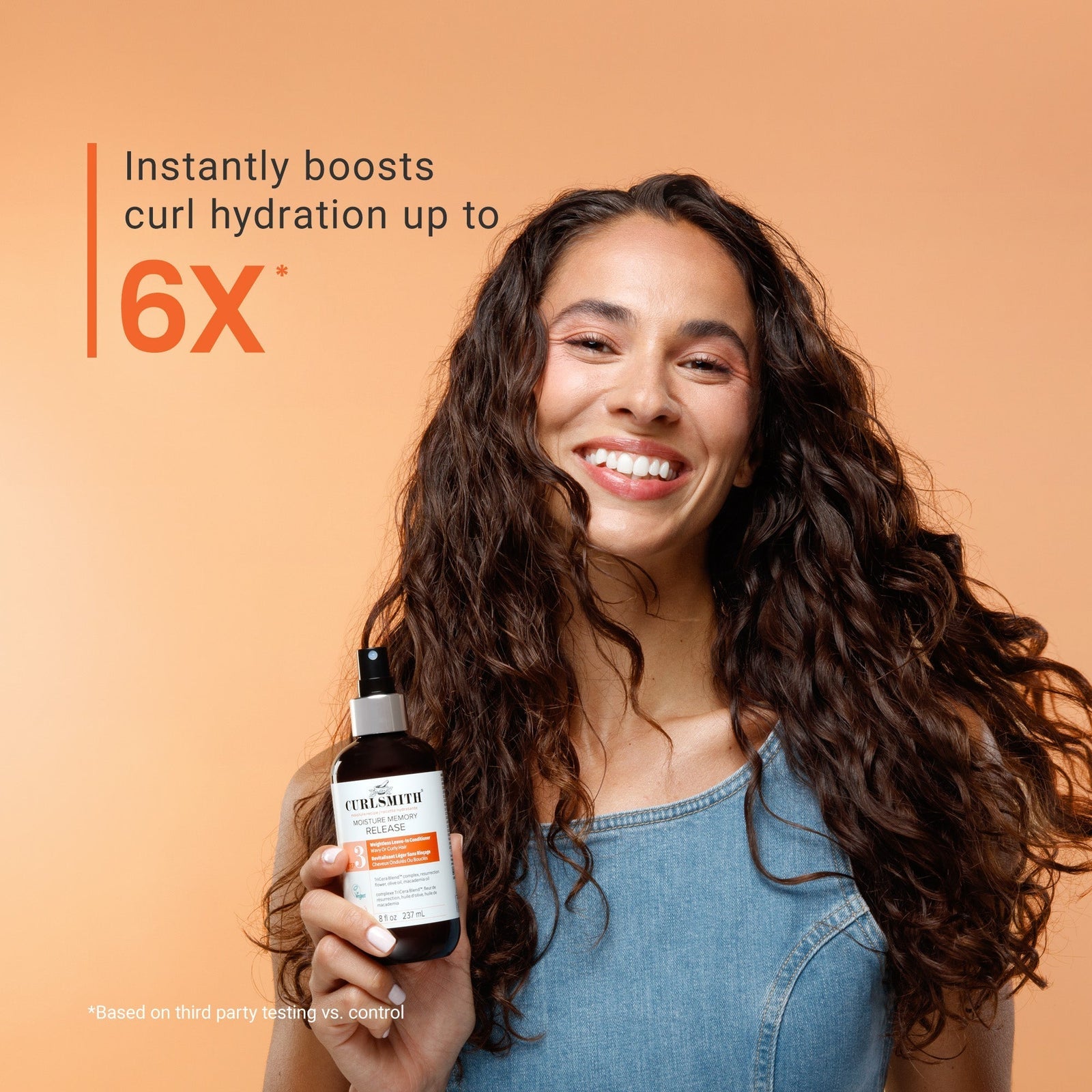 Woman holding a bottle of hair care product with text about curl hydration on an orange background